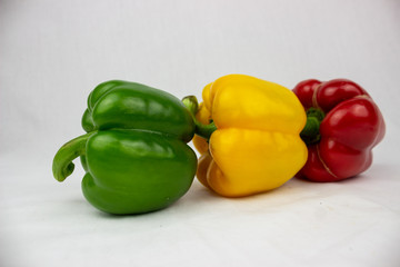 Three bell peppers, red, yellow and an orange one with white background