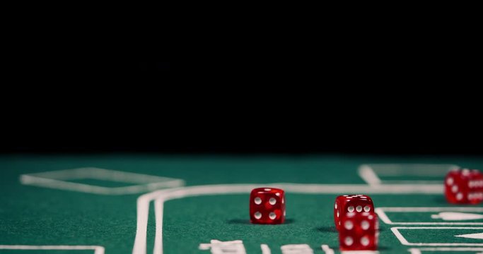 Close up of male hand rolling the dice on green poker table with black background shot in 4k super slow moton