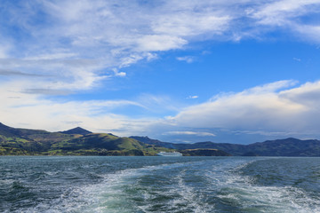 The coastline of Akaroa Harbour on Banks Peninsula, New Zealand. A cruise liner, in the middle of the photo, is dwarfed by the scenery