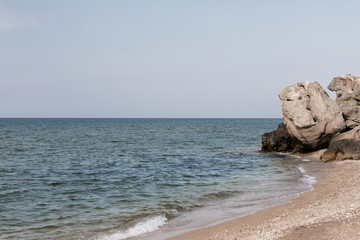 Sea coast with yellow sand, rock, against the blue sky