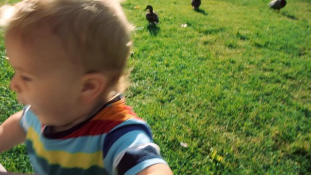 Toddler turns and charges towards camera, hitting the lens with his hand