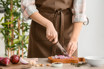 Obraz na płótnie Canvas Woman cutting fresh raw onion in kitchen, closeup