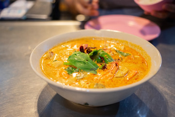 A bowl of hot and spicy tom yum kung on table, Thai street food