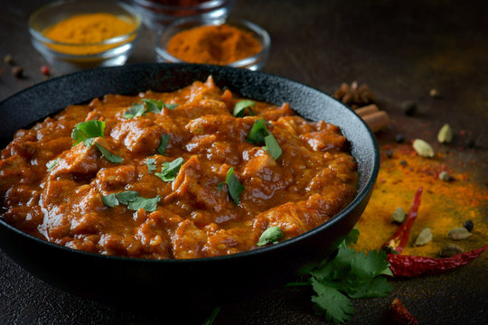 chicken curry with spices on a dark background