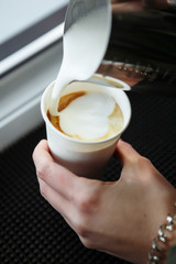 Barista draws milk over a coffee - making latte art for cappuccino