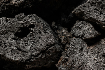 Porous black stones with texture. Close-up. Structure shot with black background. Wallpaper concept.