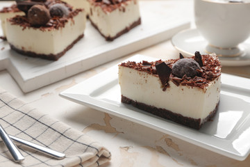 Plate with piece of tasty chocolate cheesecake on table