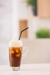 Glass cup of tasty iced coffee on table in cafe