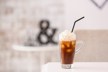 Glass cup of tasty iced coffee on table in cafe