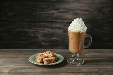 Glass cup of tasty iced coffee with cookies on wooden background