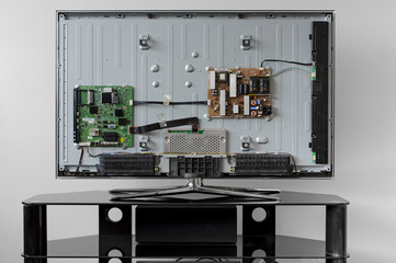 Disassembled TV is on a black table, prepared for repair.