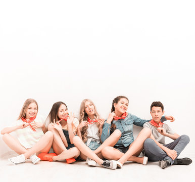 cute smiling tenagers sitting on the floor with legs crossed