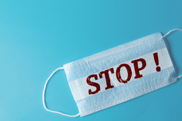 White medical mask with the inscription STOP, blue background