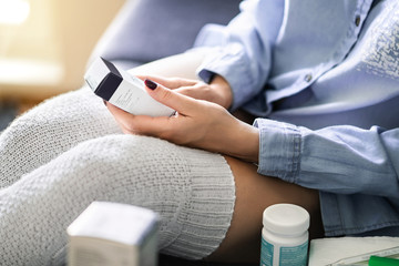 Medicine for flu, virus or pain. Ill woman reading label information of a medical product....