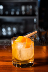 Orange cocktail with ice cube and orange zest.