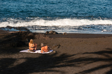 couple on the beach tenerife sunbathe on black sand