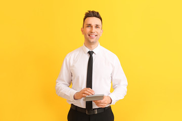 Young man with calculator on color background