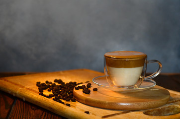 Low key photo of a cup of trendy layered Dalgona coffee on a cutting board