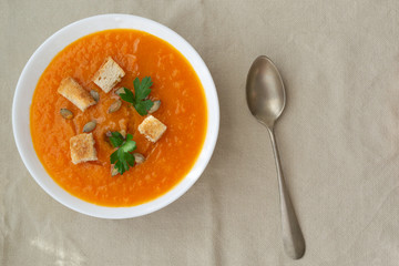 Pumpkin and carrot soup with seeds, crackers and parsley. Vegetarian soup.