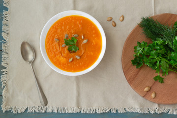 Pumpkin and carrot soup with seeds, crackers and parsley. Vegetarian soup.