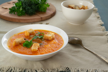 Pumpkin and carrot soup with seeds, crackers and parsley. Vegetarian soup.
