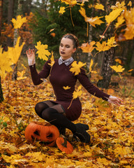   Halloween Witch with a carved Pumpkin in a autumn forest. Beautiful young woman in witches dress...