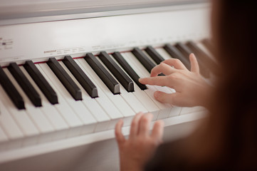 Fototapeta premium Home lesson on music for the girl on the piano. The idea of activities for the child at home during quarantine. Music concept