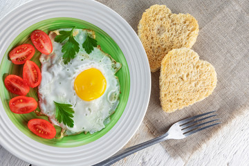 Fried egg, tomatoes, and two heart-shaped toasts. Romantic food.