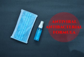 Face masks and sanitizer bottle with  red text " ANTIVIRAL/ANTIBACTERIAL/FORMULA " isolated on black background.