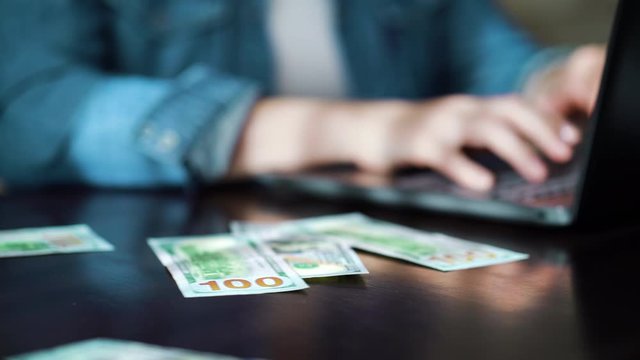 Entrepreneur working online on laptop and receiving income in dollar bills