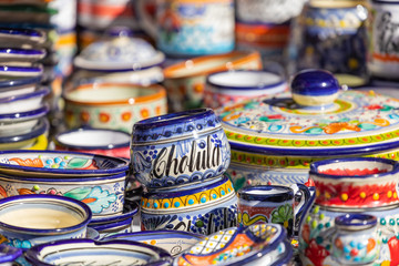 Fototapeta na wymiar Colorful traditional Mexican pottery. Talavera style. Souvenirs on sale in local market of Cholula, Mexico.