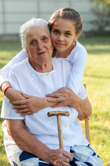 vertical close-up portrait of a ninety year old grandmother with a thirteen year old granddaughter