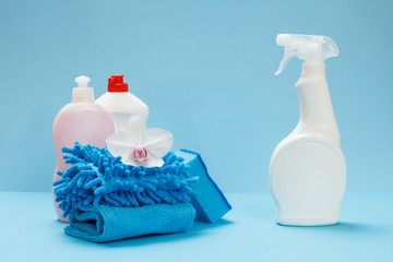 Bottles of detergent, rags and a sponge on the blue background.