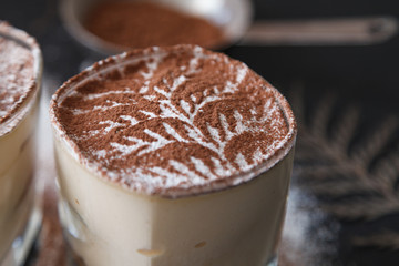 Traditional italian dessert tiramisu on glass on the black background