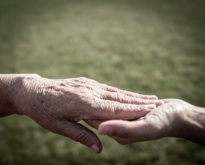 Young woman holding elderly hands