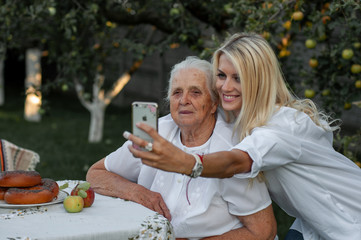 horizontal closeup photo of a charming young european woman taking a selfie with her grandmother