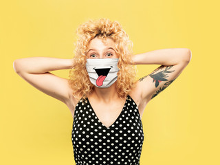 Crazy happy. Portrait of young caucasian woman with emotion on her protective face mask isolated on...