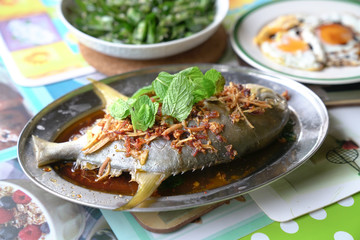 Steamed whole fish in soy sauce with ginger, garlic and mint garnish