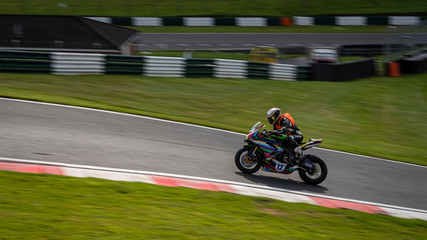 A panning image of a multicoloured racing bike passing.