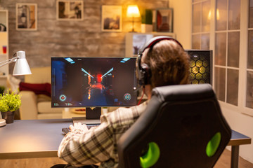 Back view of gamer male playing a shooter on his powerful PC computer late at night in the living room © DC Studio
