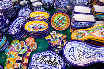 Fototapeta na wymiar Colorful traditional Mexican pottery. Talavera style. Souvenirs on sale in local market of Puebla, Mexico.