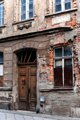 Fototapeta na wymiar Unrenovated historic brick house in the old town of Goerlitz, Germany. Beautiful wooden door, remnants of stucco on the facade, broken windows.
