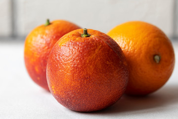 Three Sicilian blood red oranges isolated laying on the tablecloth on white brick wall background