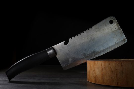 Old bent cleaver stuck on wooden butcher cutting board