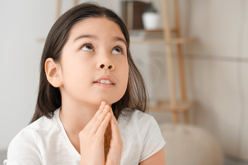 Cute little Asian girl praying at home