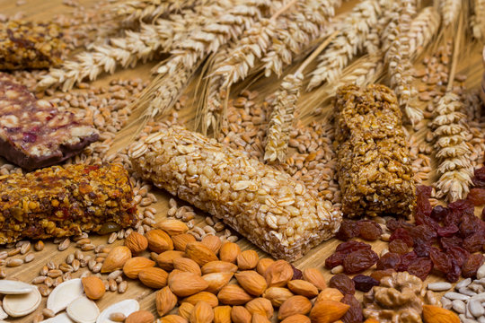 Cereal Granola Bars, Nuts, Raisins Of Wheat Sprig On Light Wooden Background