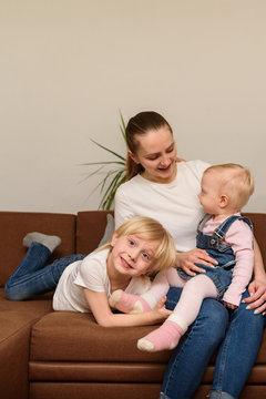 Young Mother And Two Children Sitting On Couch. Happy Family Concept. Vertical Frame