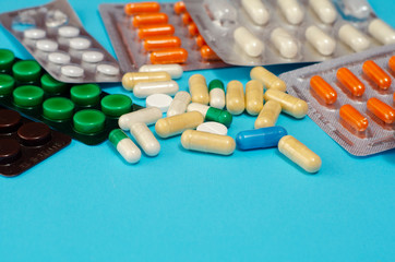Medical concept of mixed capsule pills isolated on blue background. Assorted colorful pills and capsules  close up, horizontal, copy space, selective focus, medical concept. 