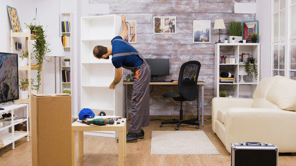 Male worker in coverall picks up assembled furniture © DC Studio