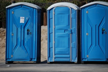 Closeup shot of three blue toilet cabins in the street